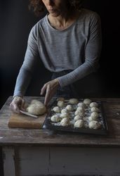 Person near tray with dough and flour on table