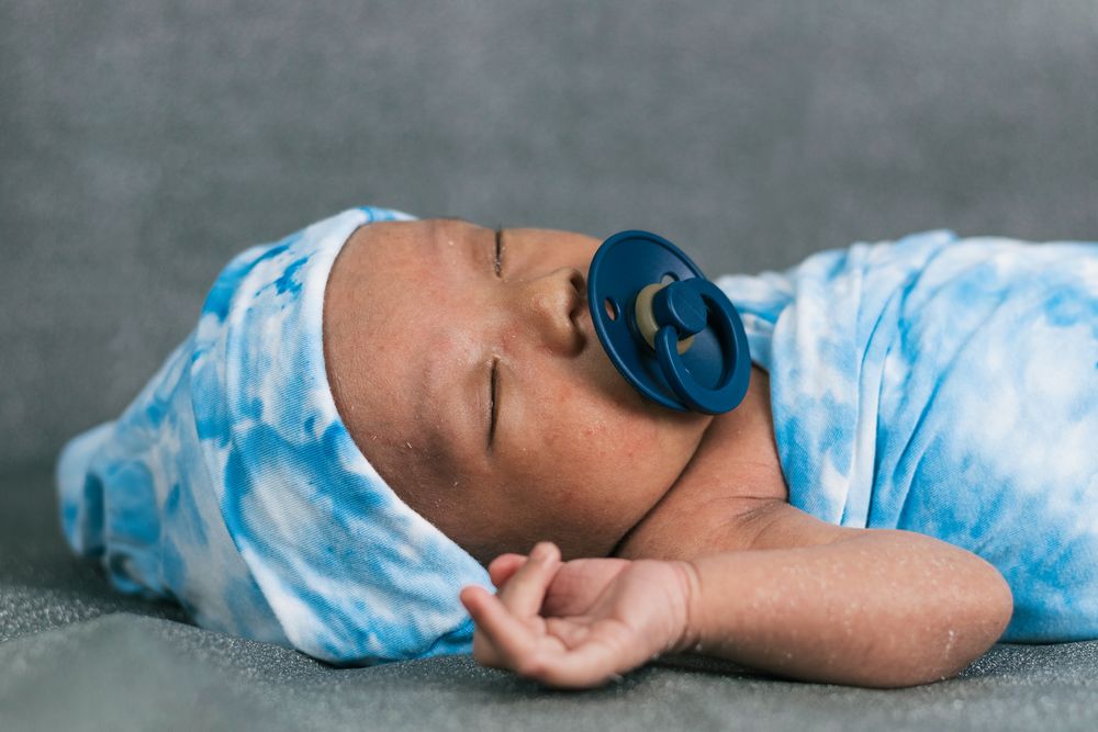 Newborn baby wrapped on soft blanket with pacifier