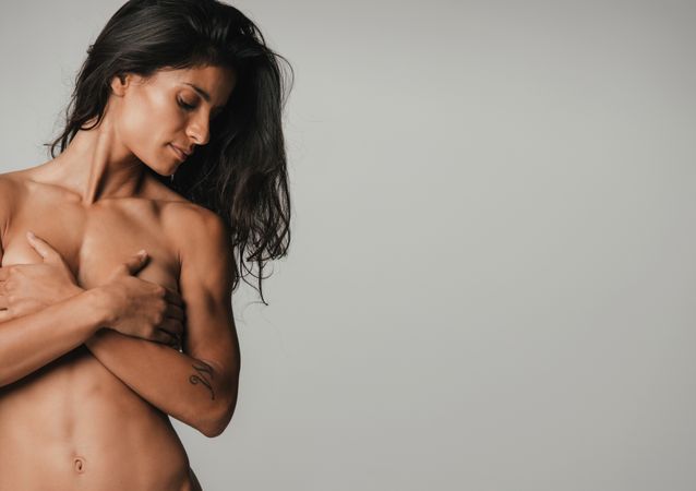 Nude fit woman covering her breasts
