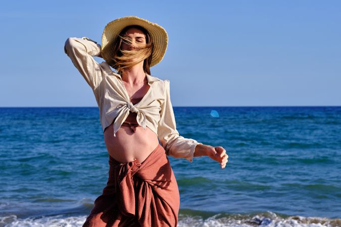 A fashion model with a hat at the beach before sunset