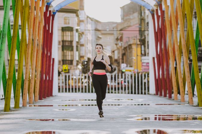 Woman with earphones running on street