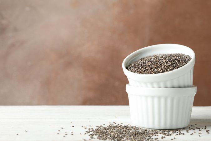 Ceramic sauce boats with chia on wooden background, copy space