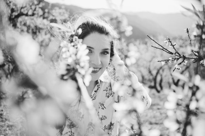 Young happy woman between trees in garden