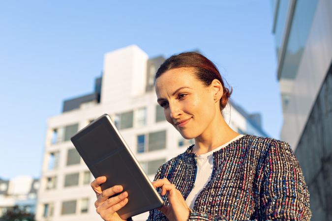 Confident entrepreneur with tablet on city street