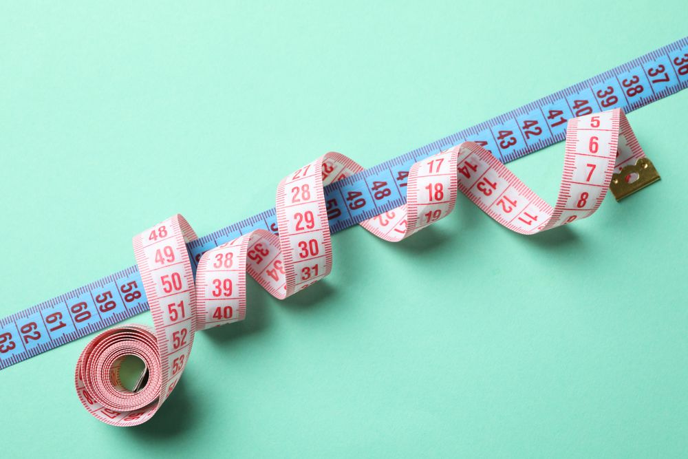 Measuring tape on mint background. Weight loss concept