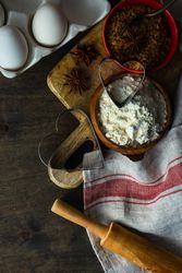 Heart shaped cookie cutters and ingredients on wooden cutting board with kitchen towel