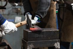 Blacksmiths forging hot iron in smithy