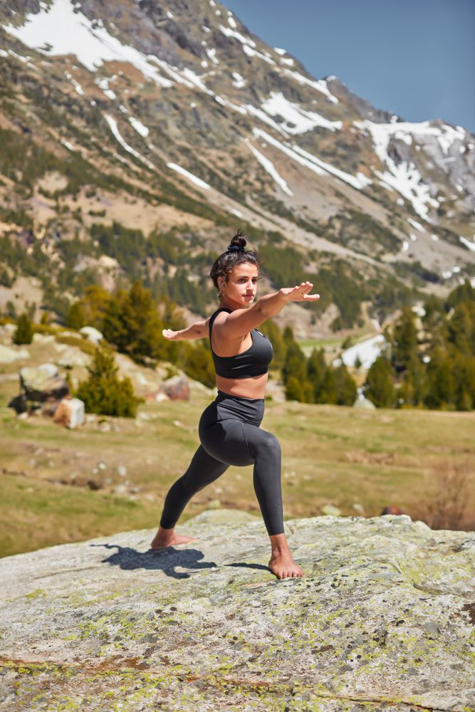 Healthy young female practicing yoga on a boulder