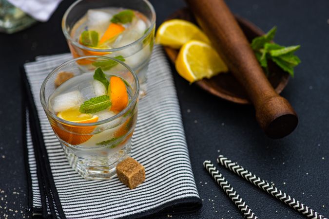 Gin and tonic cocktail on napkin with lemon and mint