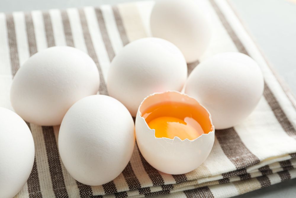 chicken eggs in kitchen towel on grey background, space for text and closeup