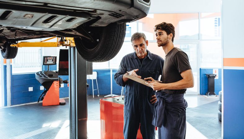Mechanics making list of repairs on a car in auto service station