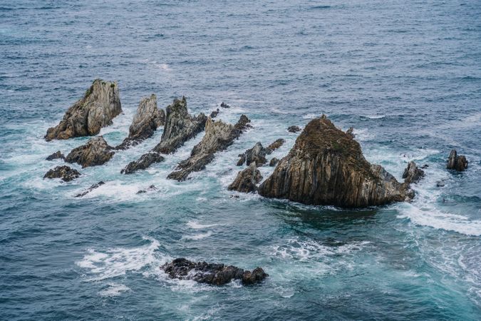 Rocky peaks surrounded by foamy water in windy day