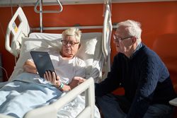 Serious female patient showing tablet to husband in clini