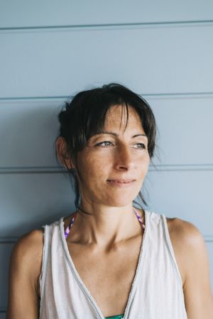 Portrait of wistful woman with ponytail leaning on wood wall