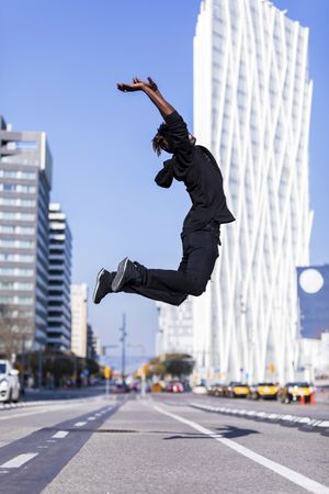 Black man wearing casual clothes jumping on city street