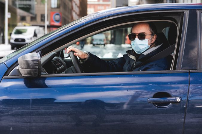MONTREAL, QUEBEC, CANADA – March 24 2020- A man wearing a mask in his car