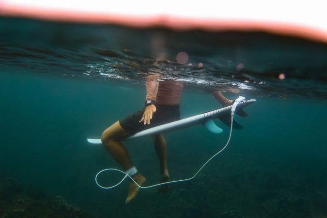 Man sitting on surf board floating in blue water