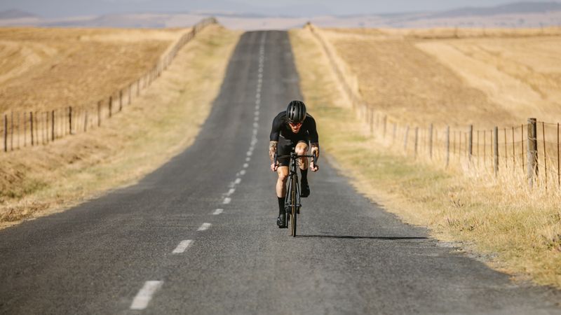 Athlete cycling on empty asphalt road