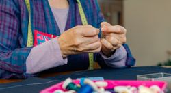 Mature female dressmaker threading a needle
