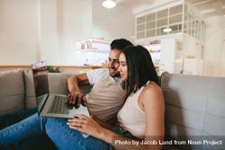 Young couple relaxing on couch with laptop at home in living room 0vgkR5