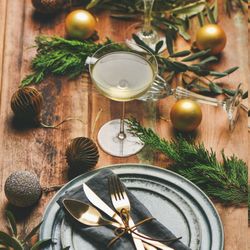 Top view of table setting with glass of Champagne, pinecone, and candle, square crop