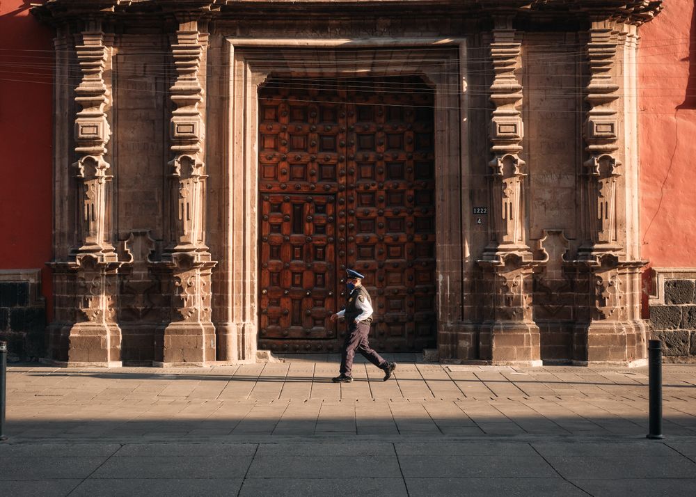 Side view of man in police uniform walking by large wooden door