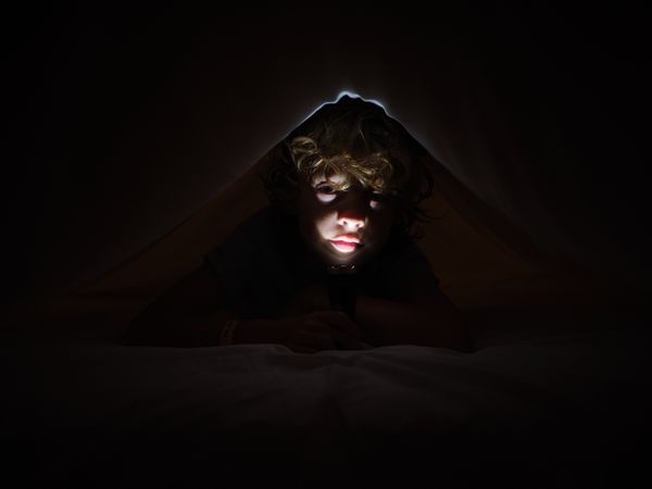 Boy with flashlight in darkness