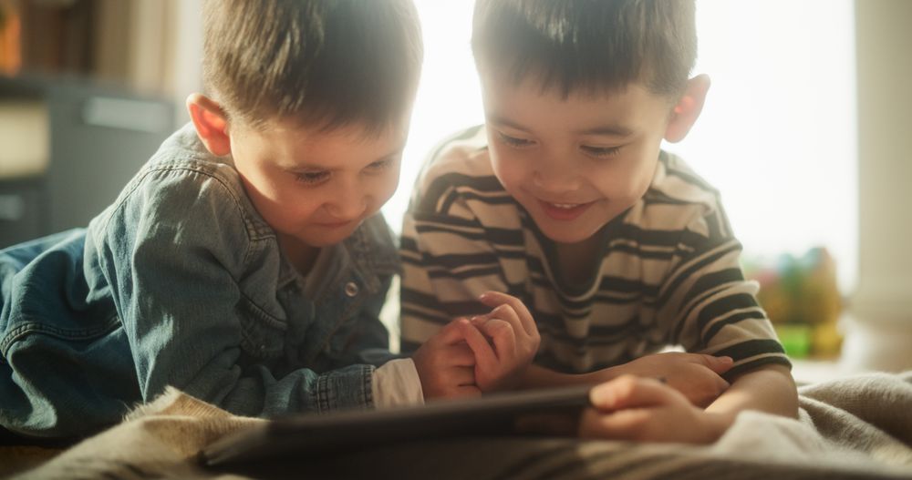 Portrait of Two Male Asian Kids Using a Digital Tablet During Weekend in their Room.