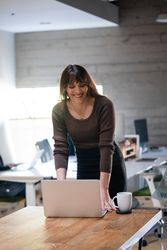 Transgender woman bending over a table in a modern open plan office