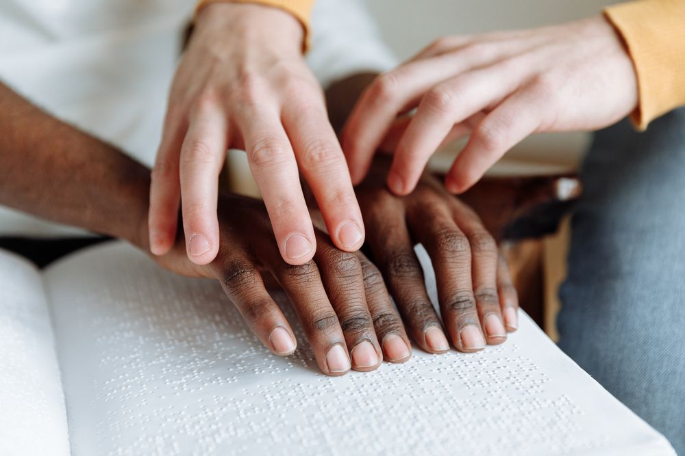 Close-up shot of a teacher teaching an visually impaired person braille system