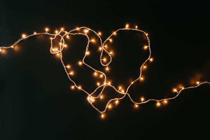 Fairy lights or Christmas lights in heart shape on dark background