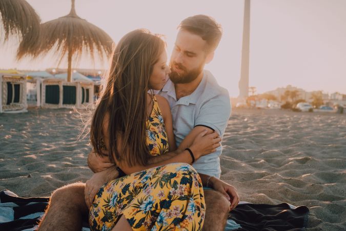 Tender couple embracing and kissing in sunlight on beach