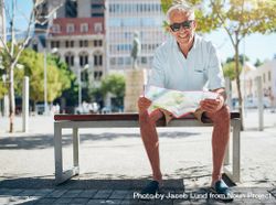 Happy man sitting on bench with a city map 412YZb