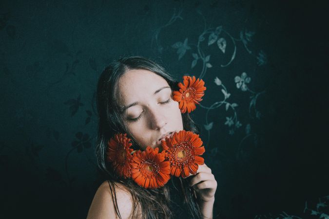 Studio portrait of woman holding gerbera flower