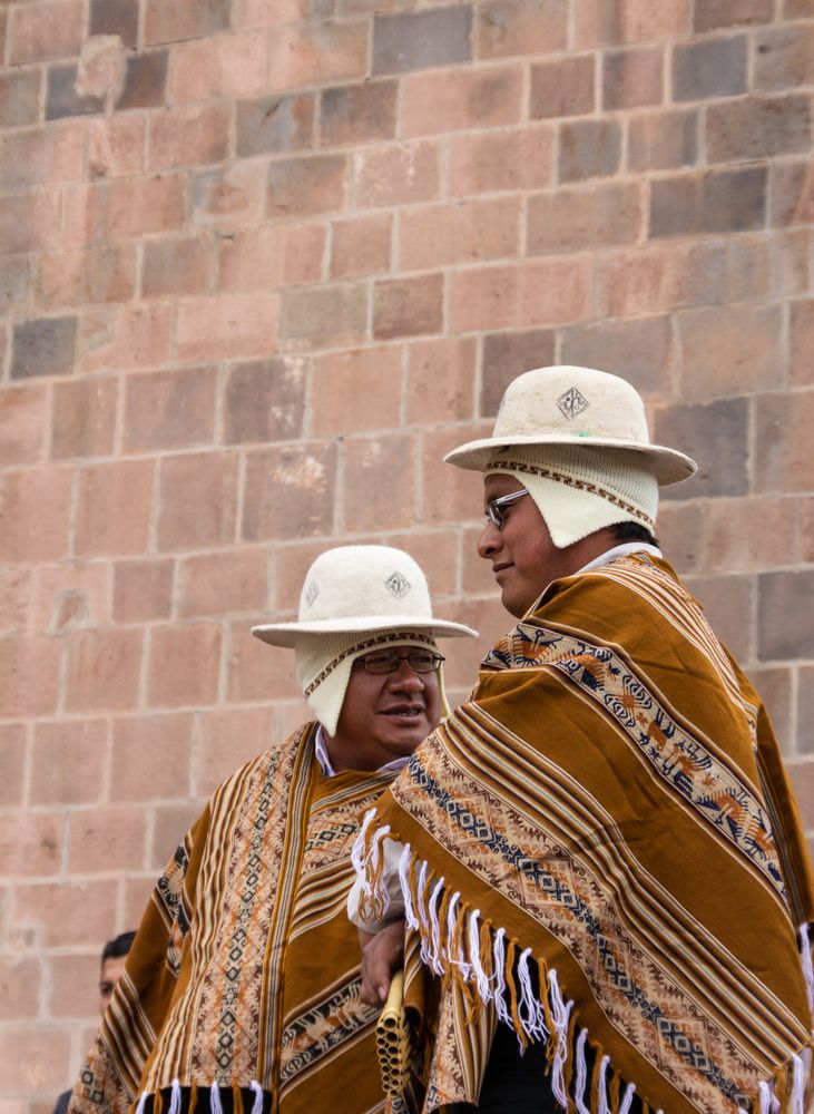 Peru - January, 02 2012: Peruvian men standing near stone wall