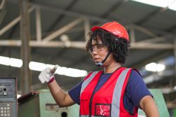 Black female worker talking with colleague standing at factory construction site