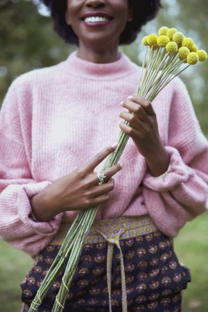 Woman in pink sweater holding yellow flower