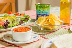 Traditional mexican food with a bowl of nachos, spicy sauce, a plate of tortillas and fresh salad