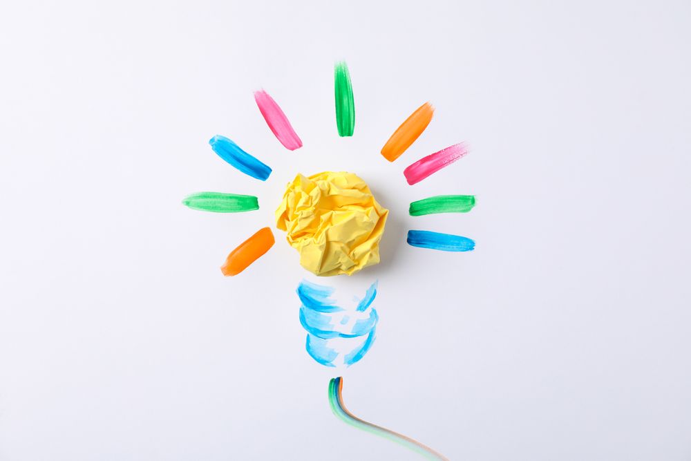 Drawn light bulb and paper ball on blank background, space for text