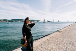 Stylish female holding hair and looking away on embankment
