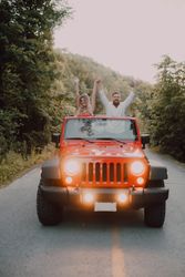 Loving couple sitting on car on road near forest