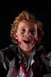 Vertical photo of a boy disguised as a zombie with an expression of having fun