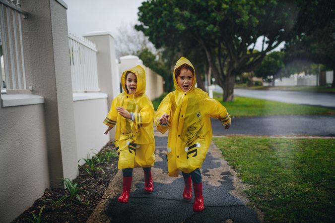 Twin sisters in waterproof coats in a rainy day