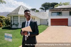 Real estate agent standing outside a house for sale 4jVXWz