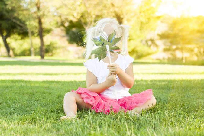 Little Girl In Grass Blowing On Pinwheel
