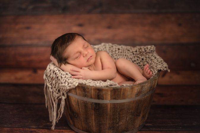 Naked baby sleeping in bucket