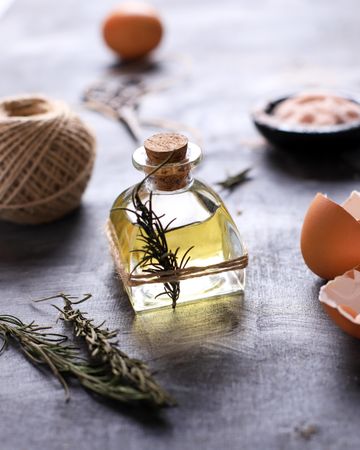 Small Bottle of Olive Oil with herbs above Rustic Table. Ready to Cook
