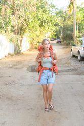 Young traveling woman walking along dirty road with backpack
