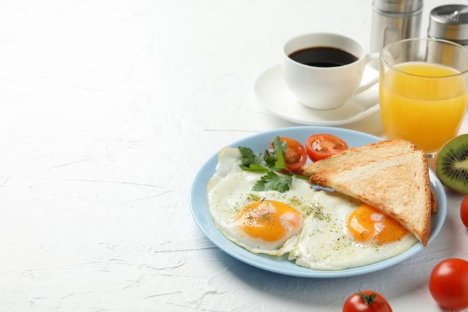 Plate of fried eggs for breakfast on blue plate, copy space
