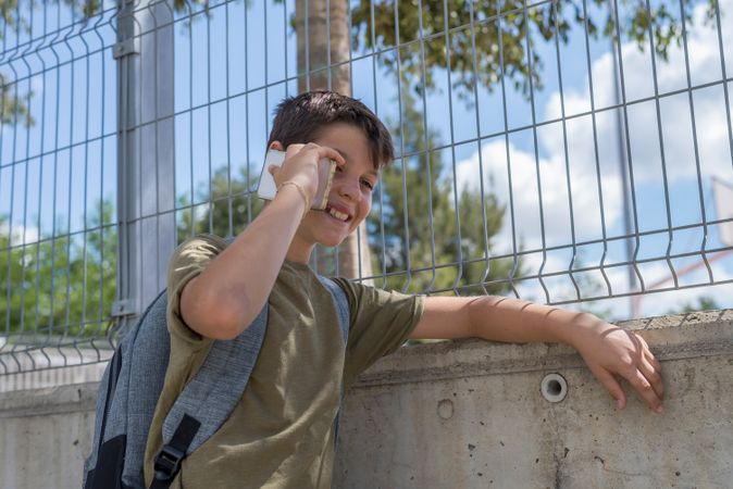 Boy talking on smartphone outside of school yard
